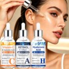 Woman applying face serum with a dropper next to the three serum bottles